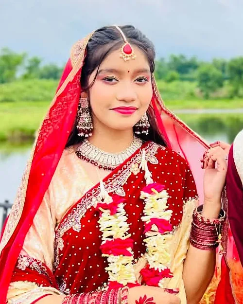 Orna in a red and gold saree with a tikli and rose garland